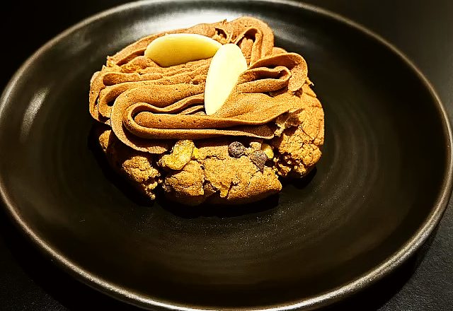 A cream-topped cookie on a black plate