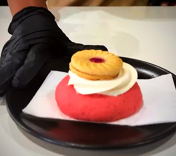 A strawberry swirl cookie topped with cream and a jam biscuit