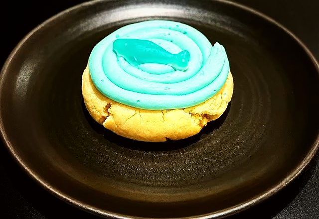 A cookie topped with teal frosting and a sweet