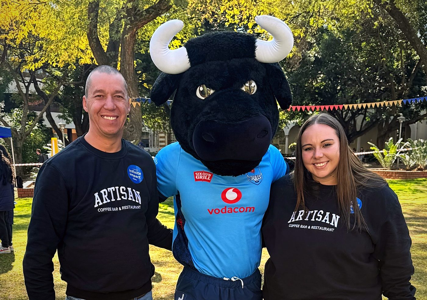 Our owner and head chef in Artisan sweaters with the Bulls mascot at the UP Food Pack-a-Thon